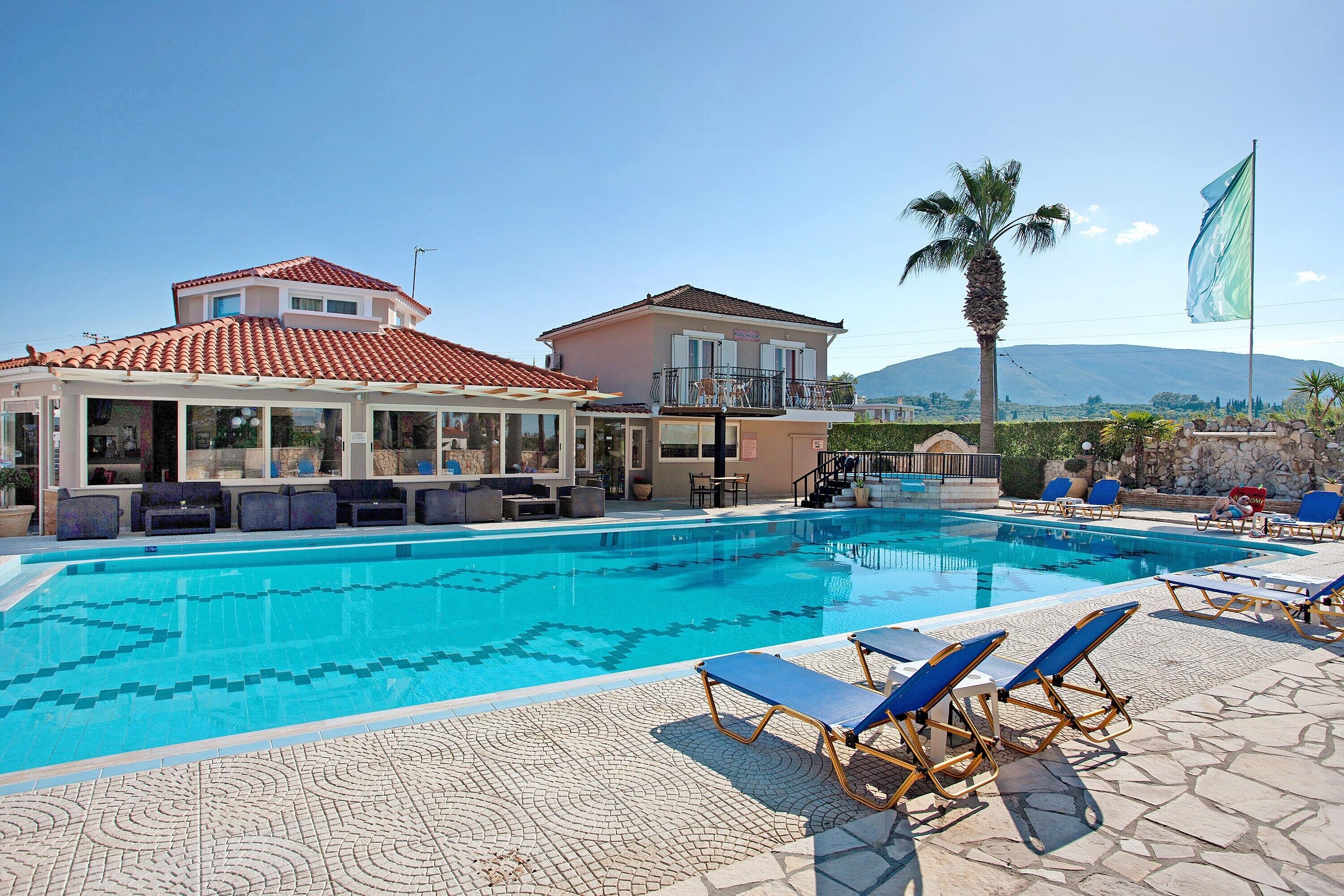 A swimming pool with lounge chairs, a covered seating area, and a mountain view.