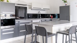 Una cocina moderna con armarios grises, una isla grande con taburetes de bar y un horno empotrado.
