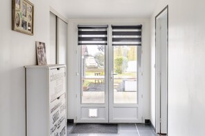 A hallway with a double door, a white cabinet with labels, and a small window.
