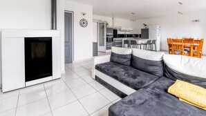 Una sala de estar moderna con chimenea, un sofá, una mesa de comedor con sillas y una cocina al fondo.