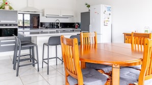 Una cocina moderna con armarios blancos, encimera negra y una mesa de comedor de madera con sillas.