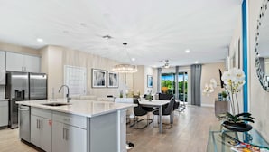 Uma cozinha moderna com eletrodomésticos de aço inoxidável, uma ilha central e um espaço de jantar com mesa de vidro.