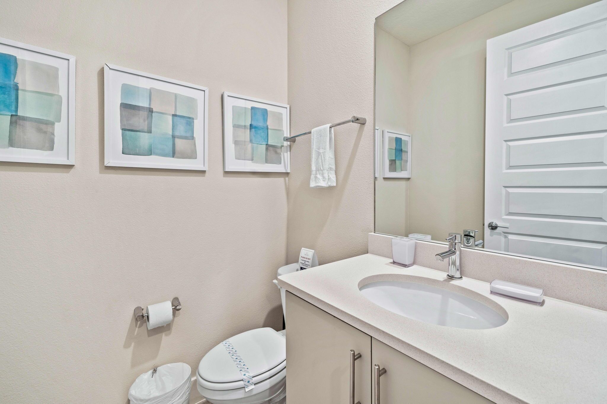 Une salle de bain avec un lavabo, des toilettes et une œuvre d’art encadrée au mur.