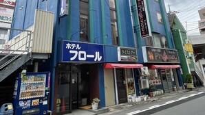 A multi-story building with a blue facade, featuring a storefront with a red awning and a sign that reads "Hotel". - HOTEL FLOR (Utsunomiya)