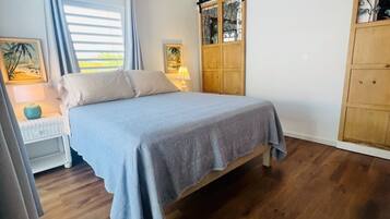 A bedroom with a bed, a nightstand, a lamp, a wardrobe, and a window with curtains.