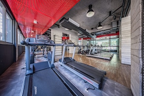 Une salle de sport équipée de tapis de course, de vélos elliptiques et d’autres appareils d’exercice.