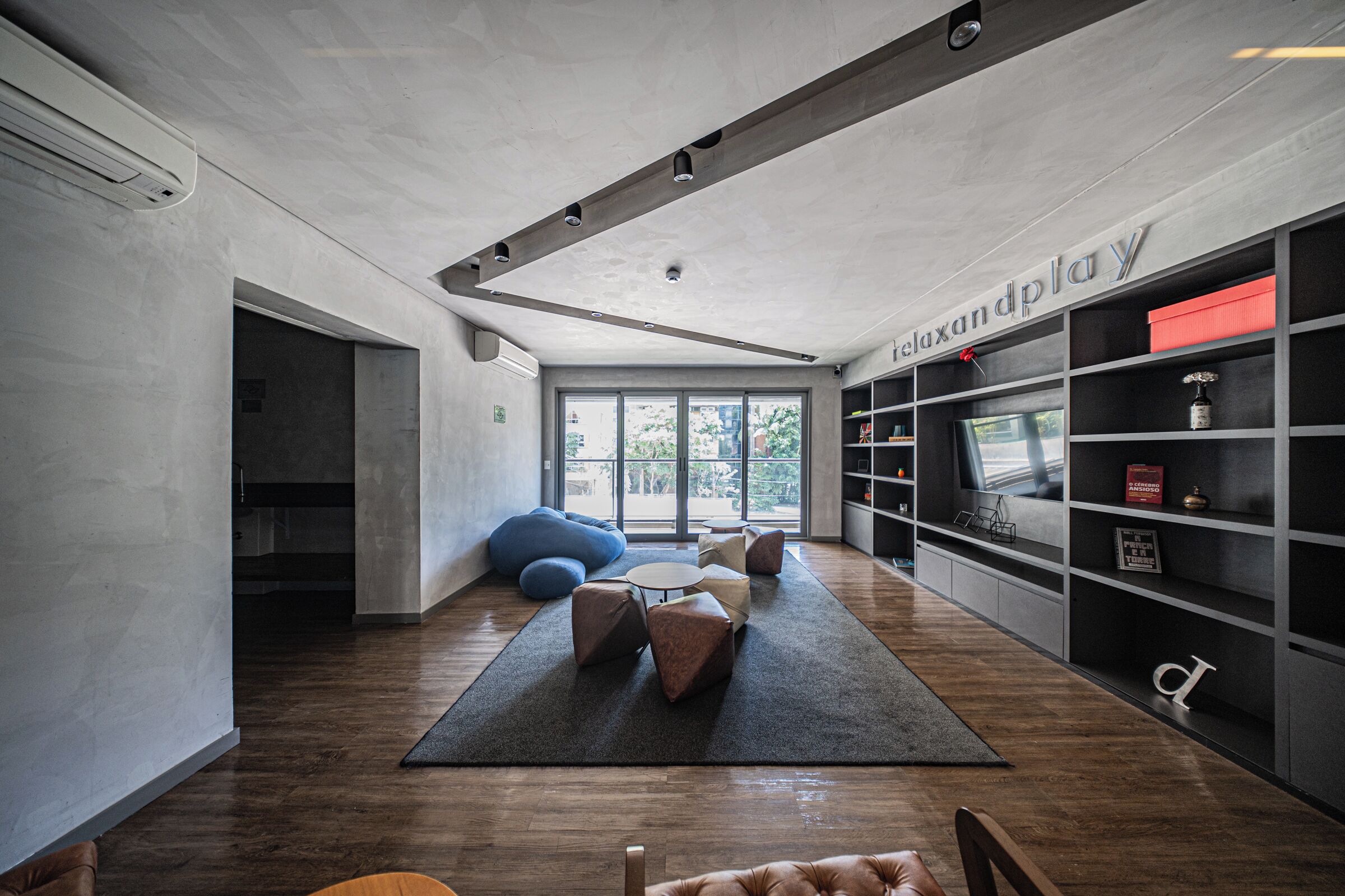 A modern interior with a large window, a black rug, and a bookshelf.