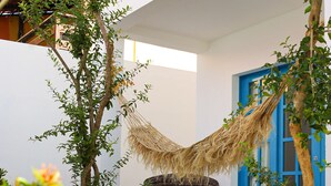 A modern outdoor seating area with a wicker sofa, a blue door, and a hanging hammock. - Vila Marinella (Jijoca de Jericoacoara)