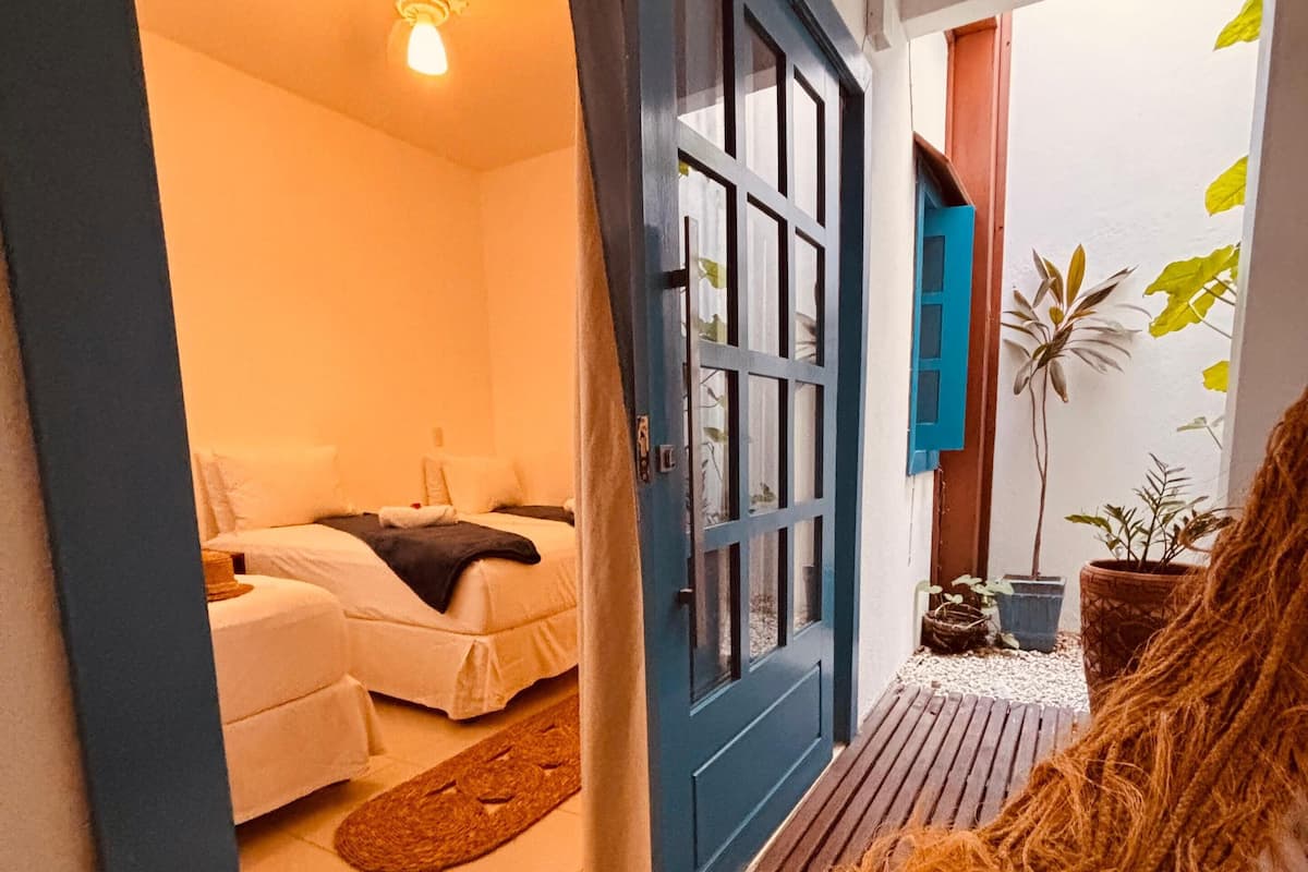 A room with a bed, a blue door, and a ceiling fan.