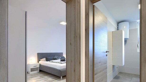 Ein modernes Schlafzimmer mit Bett, Nachttisch und Beistelltisch.