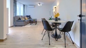 Ein modernes Wohnzimmer mit einer Couch, einem Esstisch mit Stühlen und einer Deckenleuchte.
