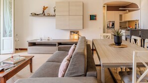 A modern living room with a sofa, dining table, and kitchen in the background.
