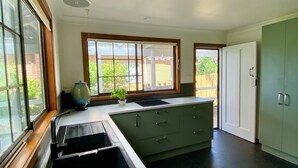 A kitchen with a large window, a sink, a countertop, and a cabinet.