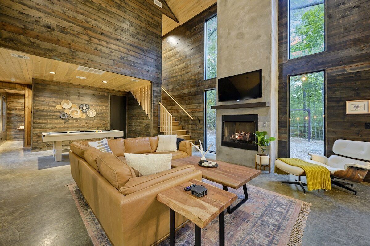A modern interior with a wooden ceiling, a fireplace, a sofa, and a dining table.