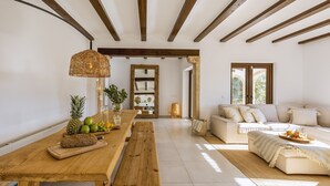 Un salón amplio con una mesa de comedor de madera, un sofá y un ventanal que proporciona luz natural.