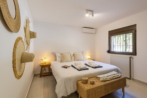 Ein Schlafzimmer mit einem großen Bett, zwei Nachttischen, einem Fenster mit Gitterstäben und einer Heizung.