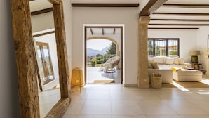 Un salón amplio con un espejo grande, un sofá y un sillón de mimbre.