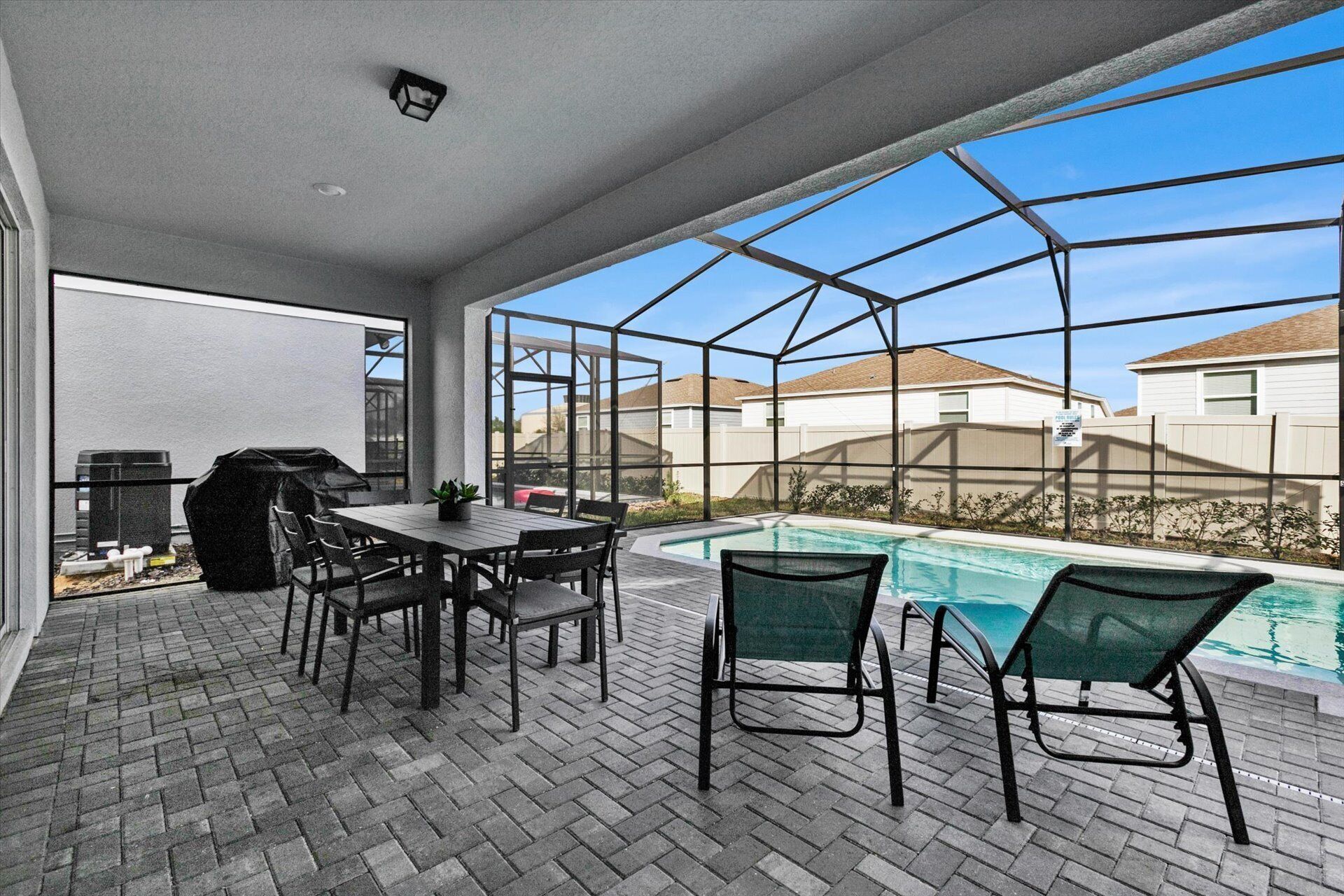 Een terras buiten met een zwembad, een barbecue en een tafel met stoelen.