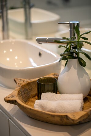 A bathroom sink with a white vase and a wooden tray with a towel and a glass. - Luxury Adelaide Retreat  | Steps to Top Dining & Festivals (Norwood)