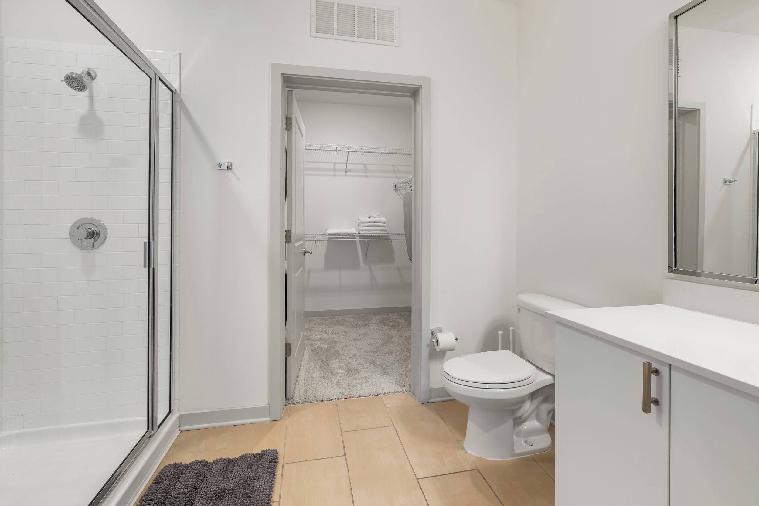 Un baño moderno con cabina de ducha de vidrio, inodoro y vestidor.