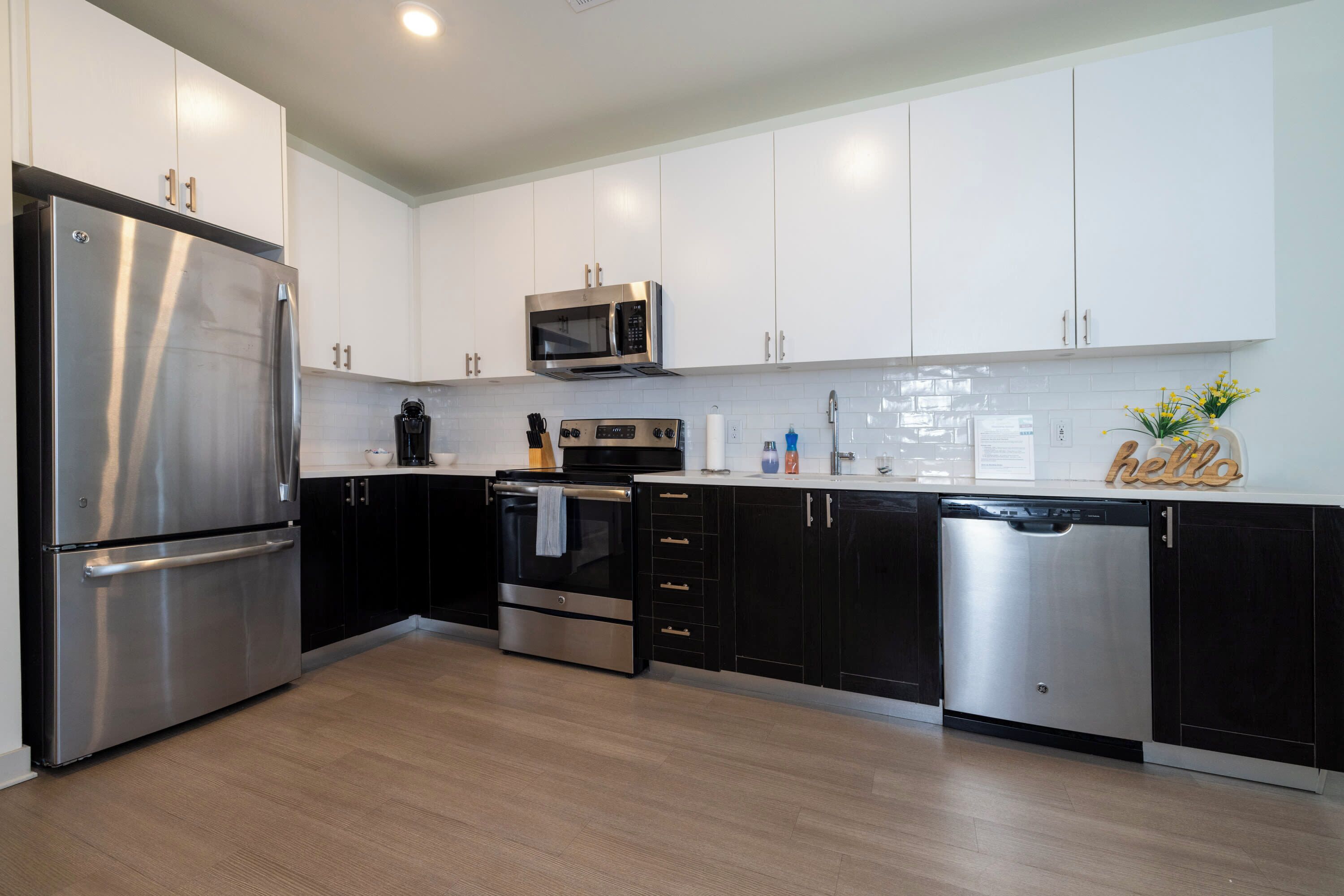 A modern kitchen with stainless steel appliances, black and white cabinetry, and a clean, minimalist design.