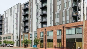 Un immeuble résidentiel à plusieurs étages, doté de balcons, d’une façade en briques et de grandes fenêtres.