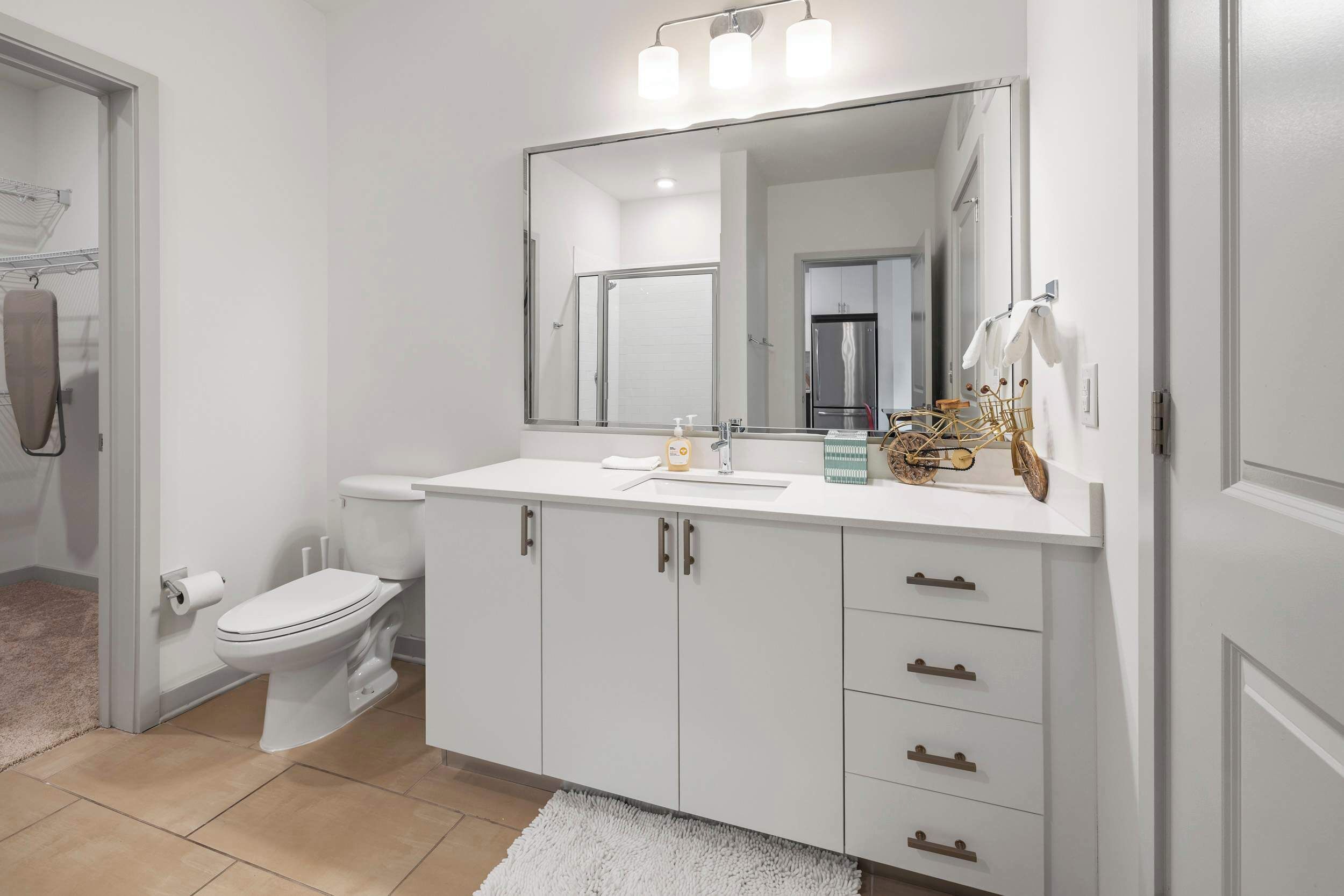 Une salle de bain moderne équipée de toilettes, d’un lavabo, d’un miroir et de meubles de rangement.