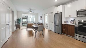 Une cuisine moderne avec des meubles blancs, des appareils en acier inoxydable et un coin repas comprenant une table et des chaises.