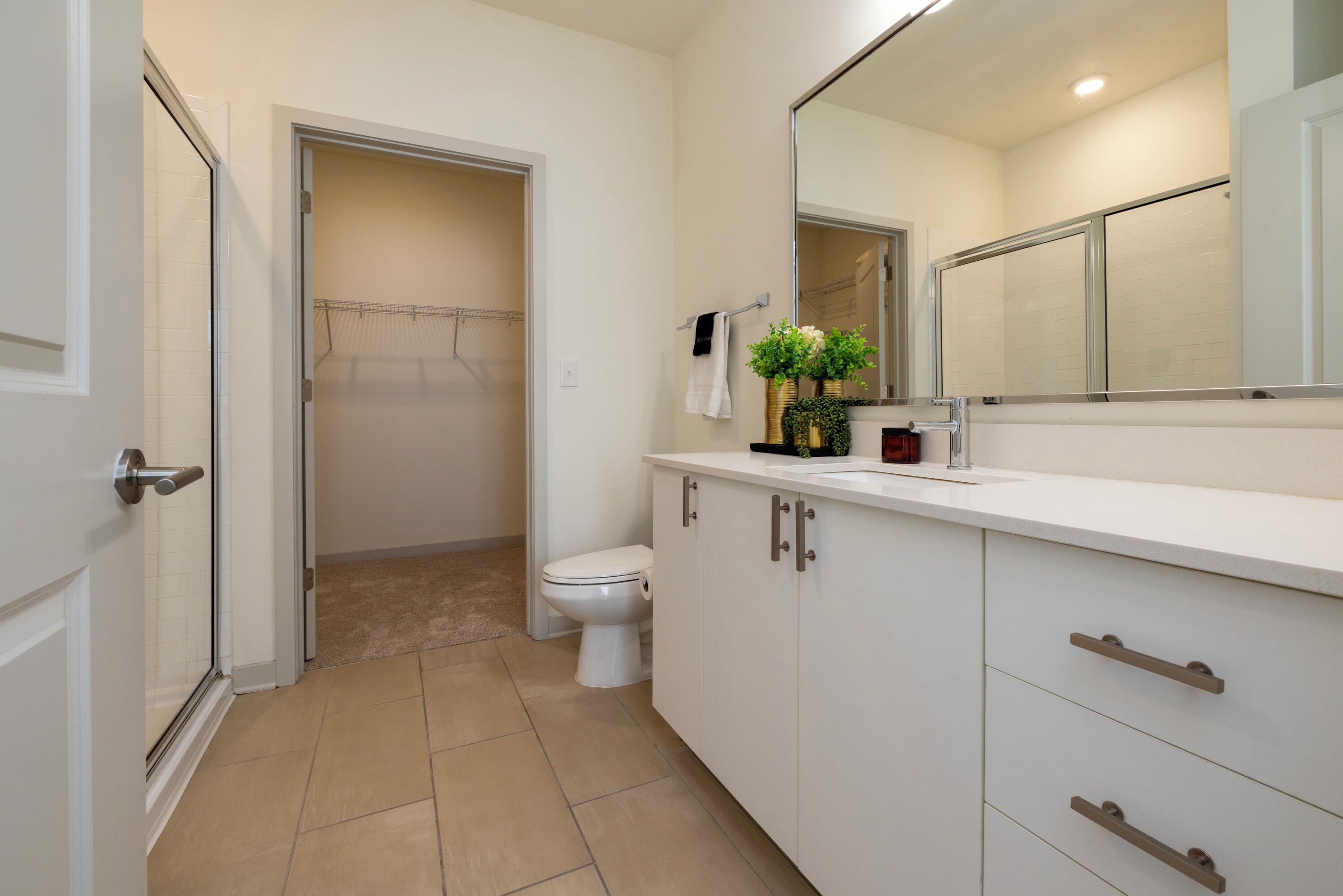 A bathroom with a toilet, a shower area, and a vanity with a mirror.