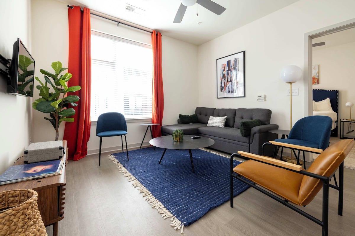 Un salon moderne avec un canapé, des fauteuils, une table basse et un téléviseur.