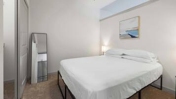 Ein Schlafzimmer mit einem Bett, einem Nachttisch, einem Wandbild und einer Tür.