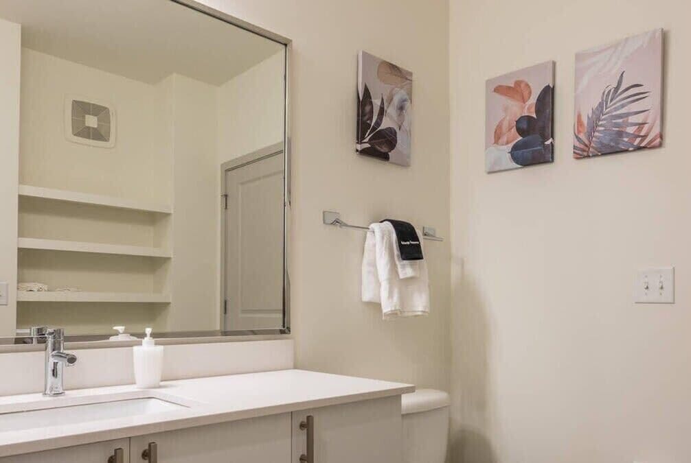 Une salle de bain avec un lavabo blanc, un miroir et un porte-serviettes.