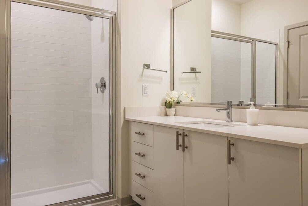 Un baño con cabina de ducha de vidrio, un lavabo con espejo y un mueble con cajones.