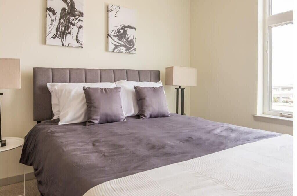 A neatly arranged bedroom with a large bed, two bedside tables, and wall art.