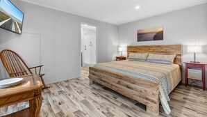 Ein Schlafzimmer mit einem hölzernen Bett, einem an der Wand montierten Fernseher, einem Holztisch und einem Stuhl.