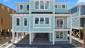 A two-story building with a balcony, a covered entryway, and a visible address number. - "Dune Our Thing II" New Construction 8 Bedroom, 8 Bathroom Oceanfront Home w/ Pool! (Holden Beach)