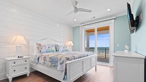 A bedroom with a bed, nightstands, a ceiling fan, a TV, and a balcony with a view. - "Dune Our Thing II" New Construction 8 Bedroom, 8 Bathroom Oceanfront Home w/ Pool! (Holden Beach)