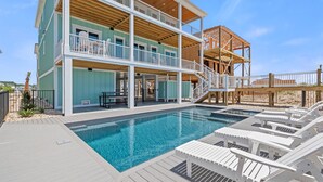 A two-story building with a pool and lounge chairs. - "Dune Our Thing II" New Construction 8 Bedroom, 8 Bathroom Oceanfront Home w/ Pool! (Holden Beach)