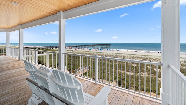 A wooden deck with white railings overlooking a beach and pier. - "Dune Our Thing II" New Construction 8 Bedroom, 8 Bathroom Oceanfront Home w/ Pool! (Holden Beach)
