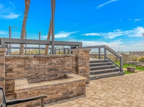 A stone wall with a metal railing, a set of stairs, and a clear blue sky.