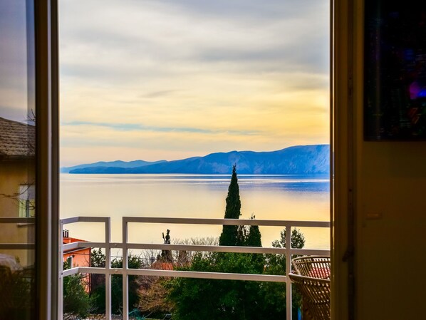 Vista desde un balcón sobre un lago con montañas al fondo.