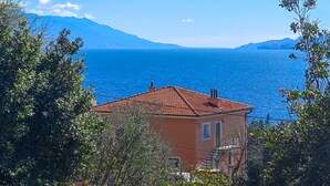 A coastal house with a red-tiled roof, a balcony, and a view of the sea and mountains. - Apartment Sanja by Interhome (Novi Vinodolski)