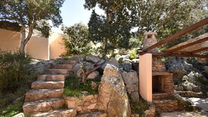 A stone staircase leading up to a stone structure with a wooden roof. - Cottage with large outdoor space and A/C (Aglientu)