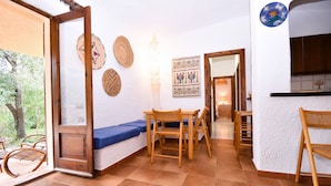 A cozy interior with a wooden dining table, chairs, and a blue cushioned bench. - Cottage with large outdoor space and A/C (Aglientu)