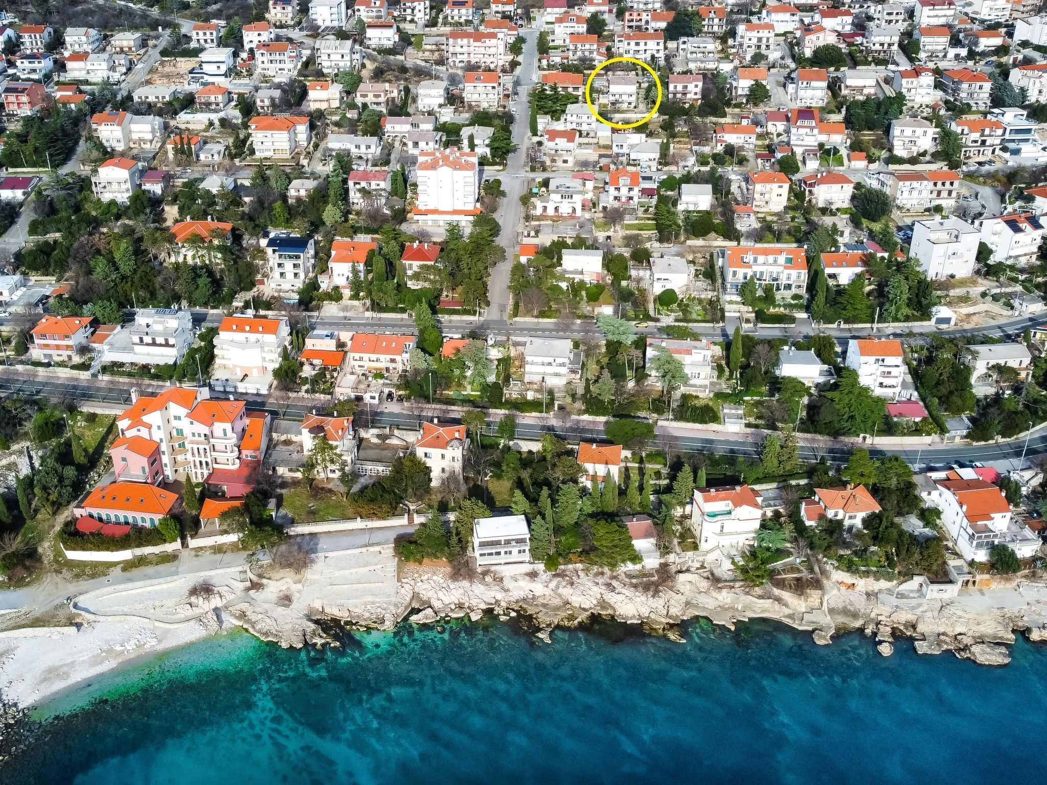 Oversigtsbillede af et kystnært boligområde med huse, veje og en strand.
