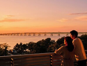 A couple on a bench overlooking a bridge and water during sunset. - EZ HOTEL KIX Seaside (Izumisano)