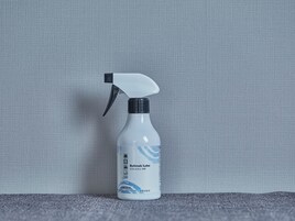 Un atomizador con etiqueta, colocado sobre una superficie texturizada frente a un fondo liso.