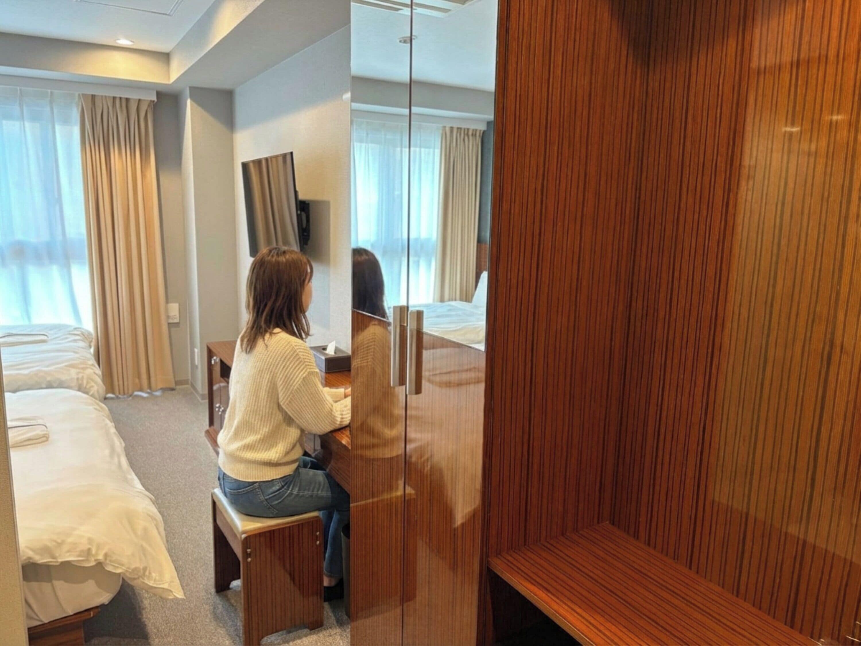 Una habitación de hotel con una cama, un escritorio y un espejo.