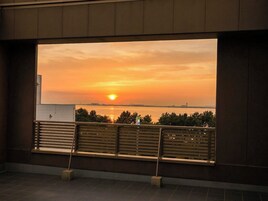 Vista del atardecer desde un balcón con barandilla y un banco.