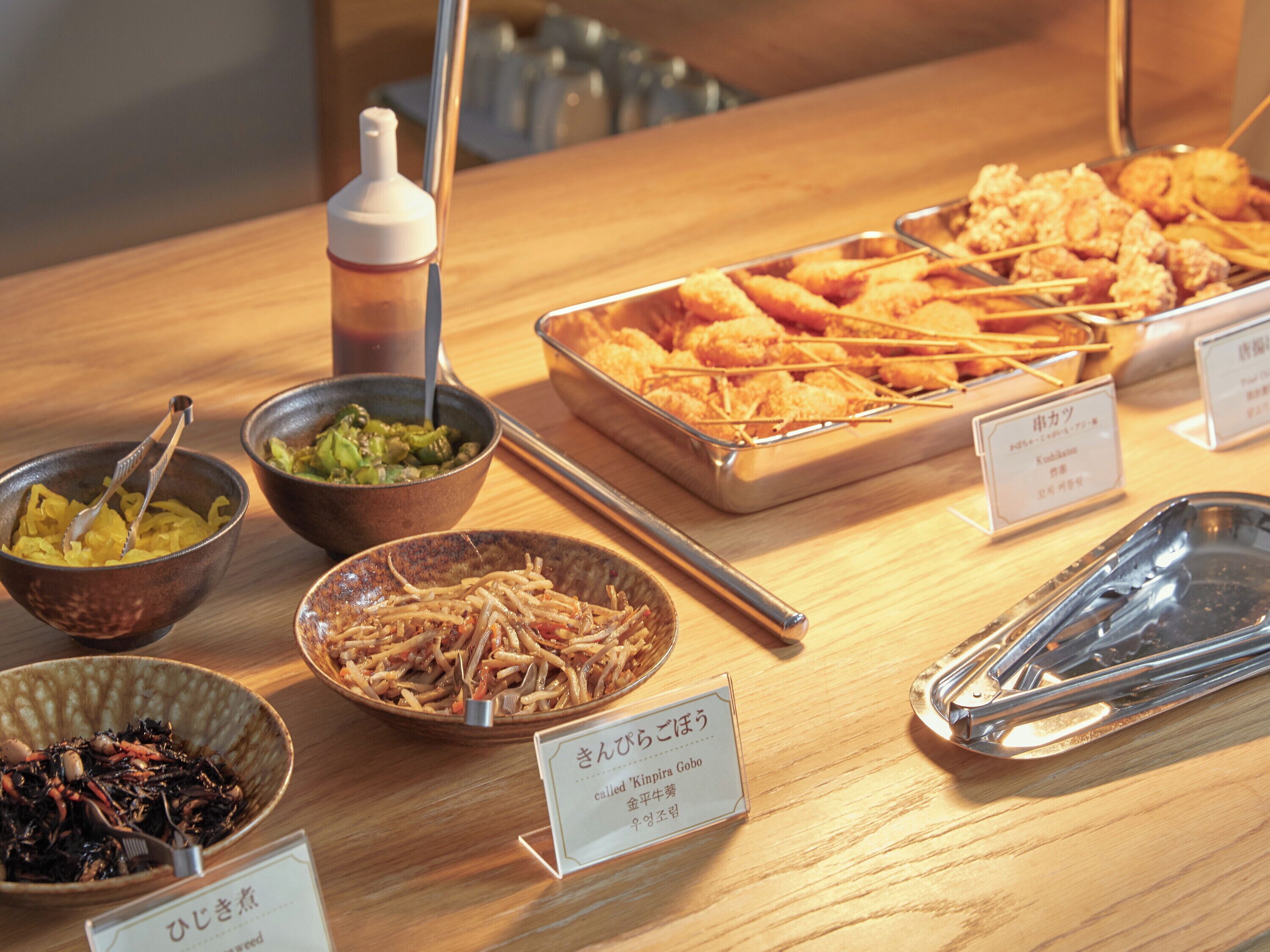 Una mesa de buffet con diversos platos, incluyendo opciones fritas y un bol de ensalada de algas.